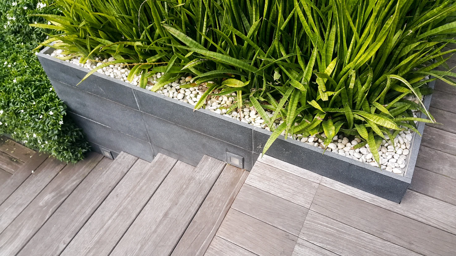 Aménagement paysager extérieur avec jardinière moderne rectangulaire en béton anthracite sur terrasse en bois composite