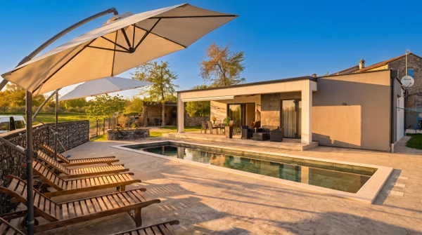 Jardin résidentiel avec piscine enterrée de forme libre, terrasse en dalles, pelouse entretenue