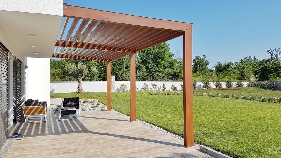 Allée de garage neuve en enrobé bitumineux noir, fraîchement posé, desservant un garage individuel avec porte sectionnelle blanche